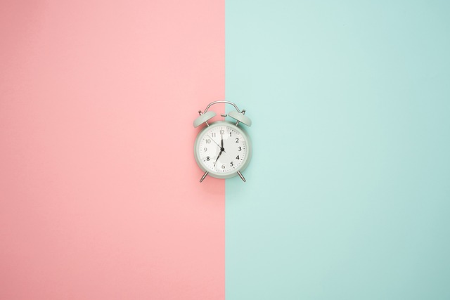 pink and light turquoise stripes behind a small analog clock