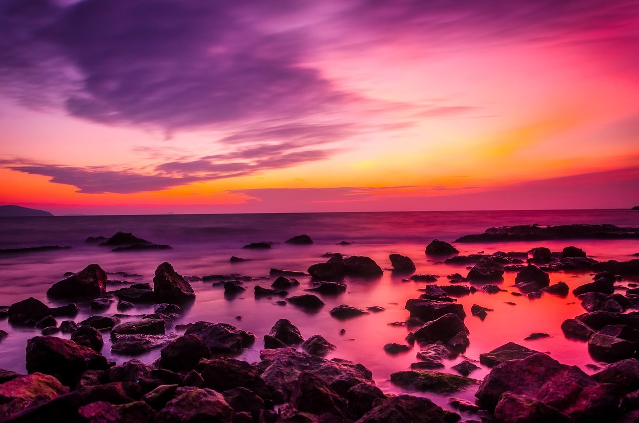 sunset on a beach with rocks on the seashore