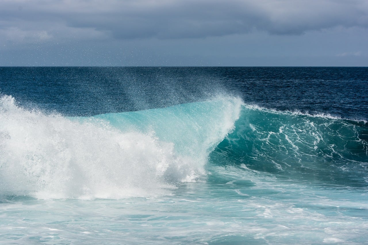 Crashing ocean waves showing colors of navy blue, seafoam green, turquoise, and white. 